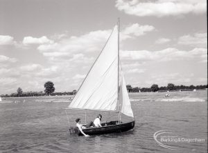 Boating at Mayesbrook Park, Dagenham, showing yacht sailing, with girl trailing hand in water, 1965