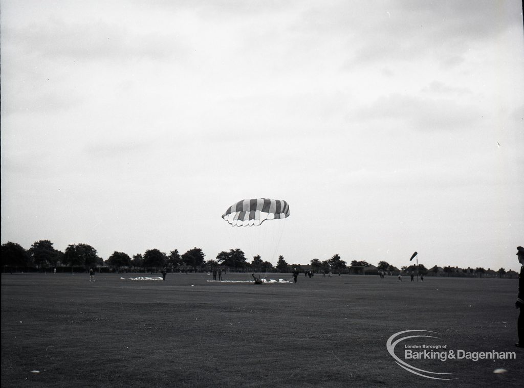 Dagenham Town Show 1965, showing a free fall parachute display by members of the Green Jackets Brigade, with parachutist on ground, 1965
