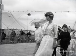 Dagenham Town Show 1965, showing a group of people including a woman in white walking past the marquee, 1965