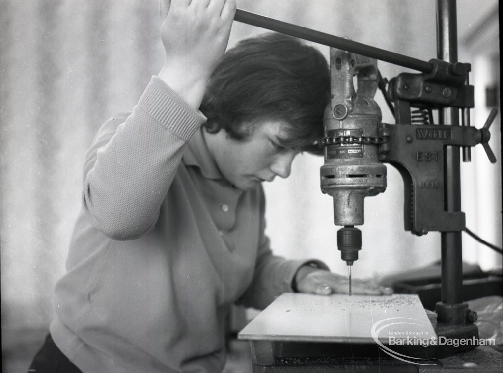 Adult Training College at Osborne Square showing a girl holding a tool and smiling in metalwork, 1965