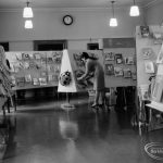 Barking Libraries exhibition at Valence House, Dagenham for National Book Week, showing member of staff looking at book display, 1966