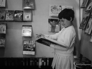 Barking Libraries exhibition at Valence House, Dagenham for National Book Week, showing smiling young girl holding large book, 1966