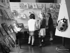 Barking Libraries exhibition at Valence House, Dagenham for National Book Week, showing three girls looking at ‘This month’s primary books’ display stand, 1966