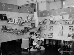 Barking Libraries exhibition at Valence House, Dagenham for National Book Week, showing cardboard cut-out of Pinocchio, frieze, and astronomy and science book display, 1966