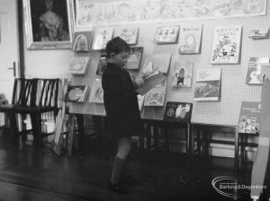 Barking Libraries exhibition at Valence House, Dagenham for National Book Week, showing child studying a book on Fairy Tales display stand, 1966