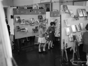 Barking Libraries exhibition at Valence House, Dagenham for National Book Week, showing two girls looking at books on display stand, 1966