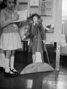 Barking Libraries exhibition at Valence House, Dagenham for National Book Week, showing cardboard cut-out of Long John Silver and a girl reading a book, 1966