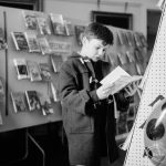 Barking Libraries exhibition at Valence House, Dagenham for National Book Week, showing a young boy studying a book on the ‘Secondary’ display bookstand, 1966