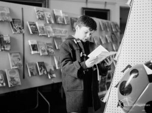Barking Libraries exhibition at Valence House, Dagenham for National Book Week, showing a young boy studying a book on the ‘Secondary’ display bookstand, 1966