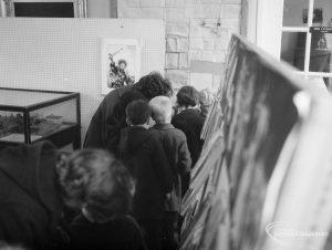 Barking Libraries exhibition at Valence House, Dagenham for National Book Week, showing a group of children standing single file by a model in a glass case, 1966