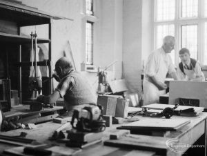 Training Centre at Eastbury House, Barking, showing men doing woodwork, with one man seated and drilling holes, and two men at bench, 1966