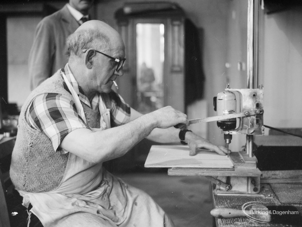 Training Centre at Eastbury House, Barking, showing men doing woodwork, with one man seated and drilling holes, and another man in background, 1966