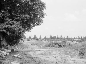 Rough middle track in Evenlode Way, Dagenham after demolition of prefabs, with rubble heaps on right and tree on left, 1966