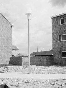 An aluminium lamp against the sky, in between two blocks of flats [possibly in Barking or Dagenham], 1966