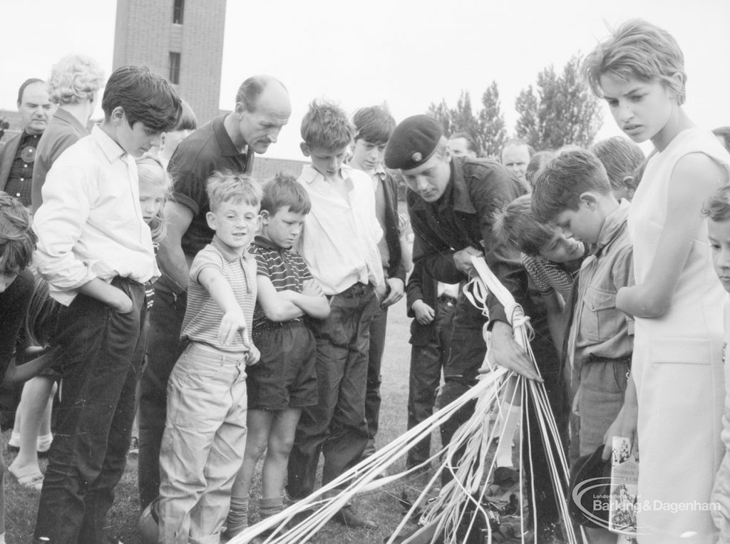 Dagenham Town Show 1966 at Central Park, showing Parachute Jumping display, with spectators watching parachutist folding parachute after drop, 1966