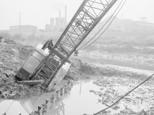 Riverside Sewage Works Reconstruction, showing Hadsphaltic digger submerged in mud in creek, leaning over fence towards water, 1966