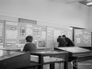 Barking Abbey 1300th anniversary exhibition at Barking Central Library, showing visitors studying wall displays on stands, 1966
