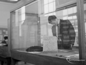 Barking Abbey 1300th anniversary exhibition at Barking Central Library, showing visitor examining objects from Abbey in glass case, 1966
