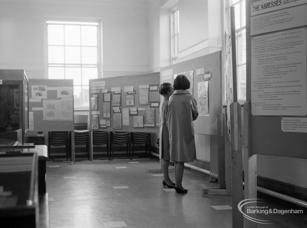 Barking Abbey 1300th anniversary exhibition at Barking Central Library, showing visitors studying wall displays on stands, 1966