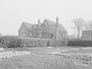 Barking Church of England School, later known as St. Margaret’s Church of England School, Back Lane, Barking, showing the western frontage, seen from Barking Abbey grounds with tree, shrubs and stones, 1967