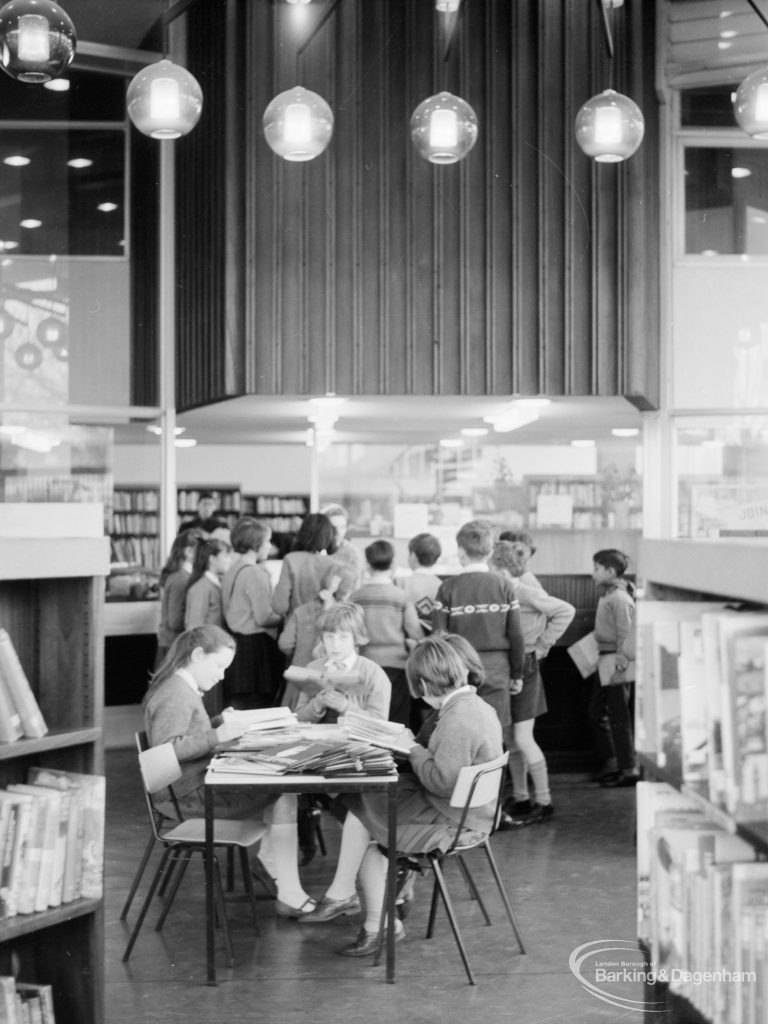 London Borough of Havering Central Library, Romford, showing junior library, with group of readers and light globes on ceiling, 1967