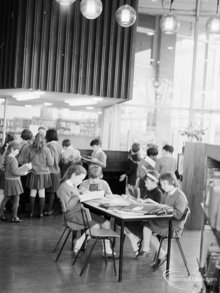 London Borough of Havering Central Library, Romford, showing junior library, with schoolgirls reading at table and groups of children looking at books in background, 1967