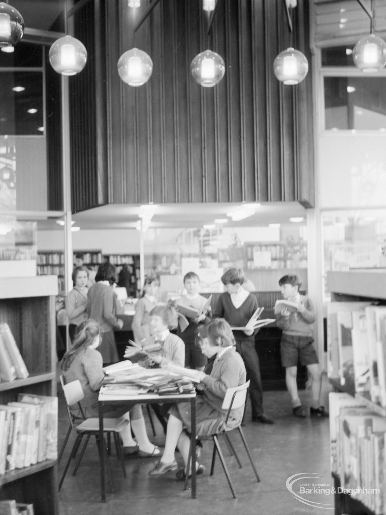 London Borough of Havering Central Library, Romford, showing junior library, with groups of readers, standing and seated, and light globes on ceiling, 1967