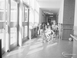 Faircross Special School, Hulse Avenue, Barking, showing three wheelchair user pupils in corridor, going to lunch, 1967