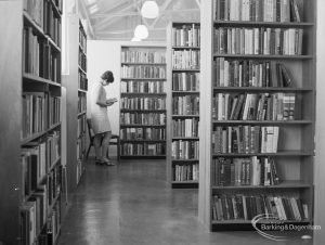 Reader standing by freestanding bookstacks in temporary Barking Central Library in old Billiard Hall, off East Street, 1967