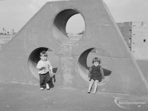 London Borough of Barking Works Department children’s playground in Oval Road North, Dagenham, showing boy and girl seated in lower holes of truncated pyramidal climbing equipment, 1967