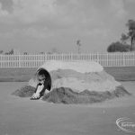 London Borough of Barking Works Department children’s playground in Oval Road North, Dagenham, showing small child emerging from sand-covered barrel, 1967