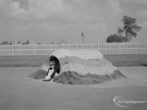 London Borough of Barking Works Department children’s playground in Oval Road North, Dagenham, showing small child emerging from sand-covered barrel, 1967