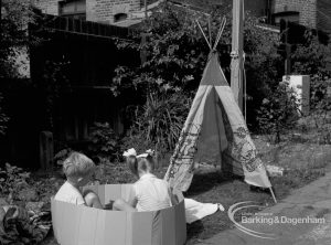 Child welfare at house at 26 – 28 Manor Road, Romford, showing girl and boy in plastic tub looking at wigwam, 1968
