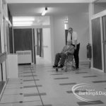 Welfare, showing Leys Avenue Occupational Centre for the Physically Handicapped, Dagenham, with member of staff pushing wheelchair user into main hall, 1968