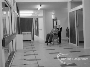 Welfare, showing Leys Avenue Occupational Centre for the Physically Handicapped, Dagenham, with member of staff pushing wheelchair user into main hall, 1968