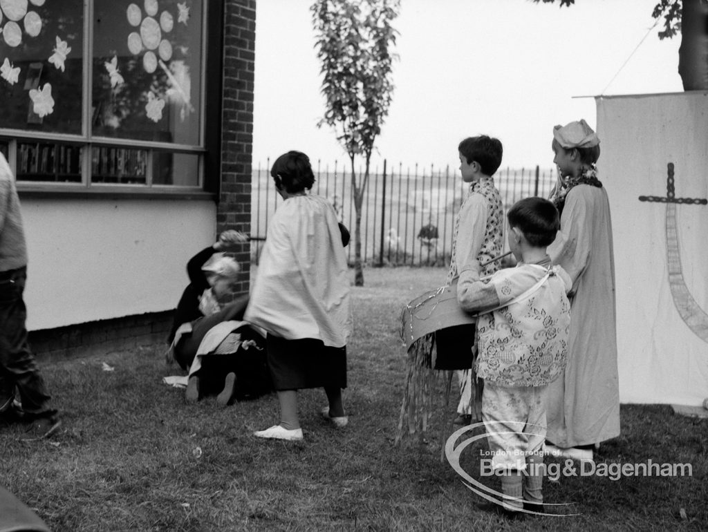 Rectory Library, Dagenham production of ‘The Price of Wisdom’ in grounds of library, produced by Mrs Jean Hickman, showing several standing players, with junior library beyond, 1969