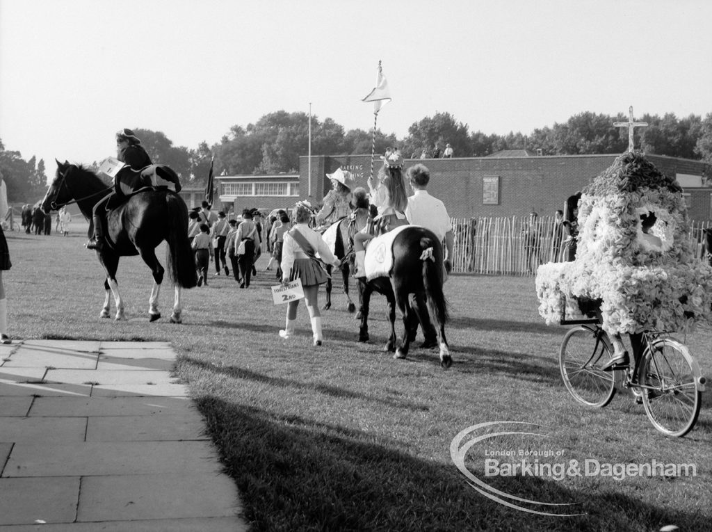 Mounted rider leading other horses and decorated bicycles at the Barking Carnival, 1969