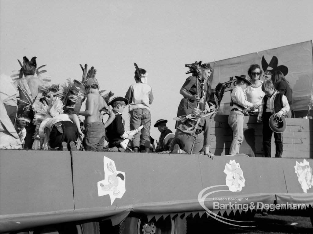 Crowds on a carnival float in Native American headdresses at the Barking Carnival, 1969