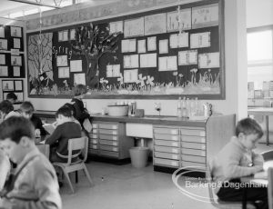 New William Bellamy Primary School, Becontree Heath, showing classroom looking north, with children seated around tables and decorated board on wall, 1970