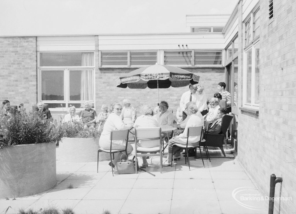 London Borough of Barking Welfare Department, Leys Training Centre Dagenham, showing groups of people standing and sitting on patio amongst flower-filled tubs, taken from east, 1971