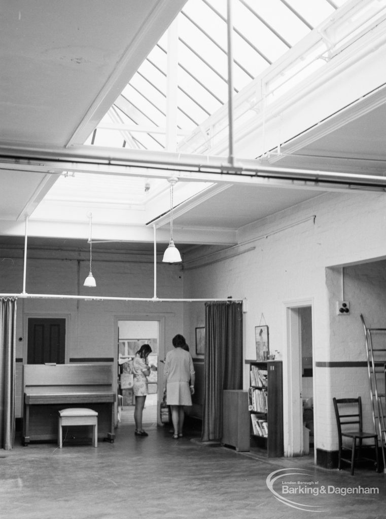 Village Infants School, Church Elm Lane, Dagenham interior [closed 23 July 1971], showing end of hall with piano and bookcase, 1971