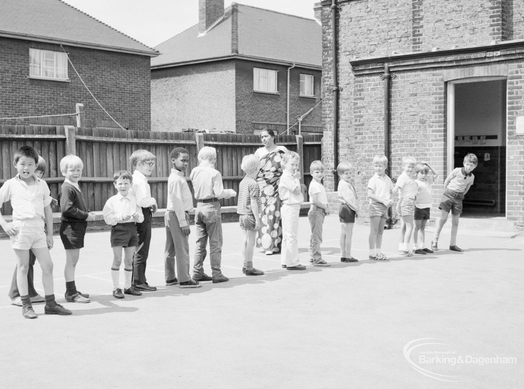 Village Infants School, Church Elm Lane, Dagenham [closed 23 July 1971], showing line of young children in playground with teacher, 1971