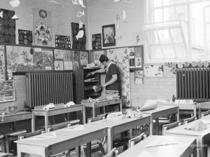 Village Infants School, Church Elm Lane, Dagenham interior [closed 23 July 1971], showing classroom with desks, children’s paintings and teacher, 1971