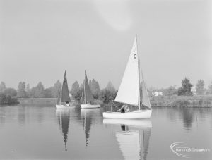 1c’ sailing boat passing before two red-sailed boats, at the Sailing Regatta in Mayesbrook Park, Dagenham, 1971