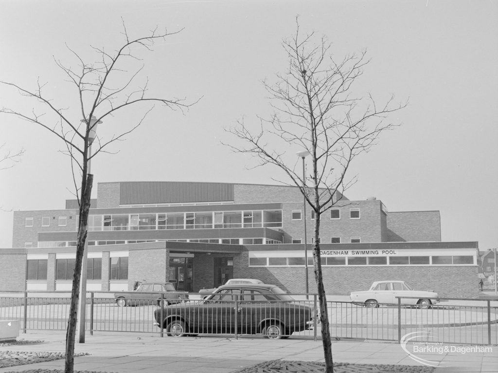 Dagenham Swimming Pool, Becontree Heath from north-east, framed between two bare spindly trees, 1972