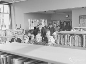 Seated and standing men and women waiting for their bus permits in Children’s Library at Rectory Library, Dagenham, 1972