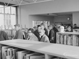 Seated group of men and women about to apply for their bus permits in Children’s Library at Rectory Library, Dagenham, 1972
