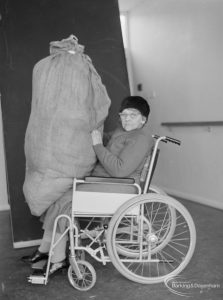 Leys Avenue Occupational Centre for the Physically Handicapped, Dagenham, showing female wheelchair user holding large sack, 1972