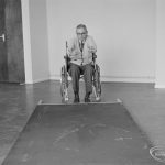 Leys Avenue Occupational Centre for the Physically Handicapped, Dagenham, showing male wheelchair user pushing over large ‘blind’ barrier, 1972