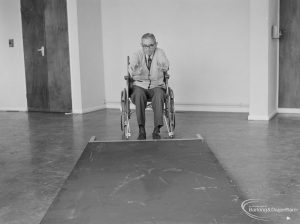 Leys Avenue Occupational Centre for the Physically Handicapped, Dagenham, showing male wheelchair user pushing over large ‘blind’ barrier, 1972